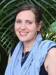 Dr Jane Fox smiling and standing in front of greenery wearing a blue scarf.