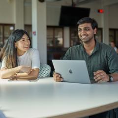 Two smiling students sitting at table