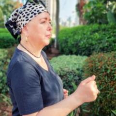 Woman wearing head scarf power walking past hedges