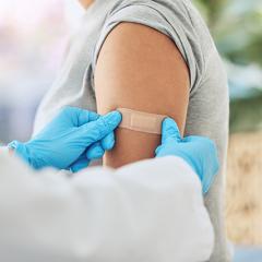 Doctor putting bandaid on person's upper arm