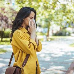 Woman blowing nose in park