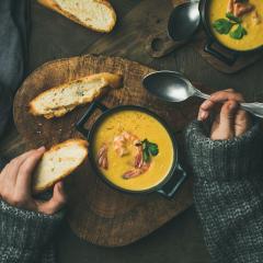 Hands holding spoon about to eat soup