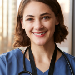 Female GP wearing blue scrubs with stethoscope, smiling. 