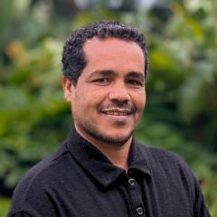 UQ's Alemayehu Mekonnen standing in front of greenery.