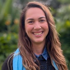 UQ's Leticia Watanabe Ribeiro standing in front of greenery in a blue scarf and jumper.