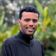 UQ's  Biresaw Alemu standing in front of greenery.