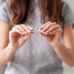 Lady in grey tshirt breaking a cigarette in half